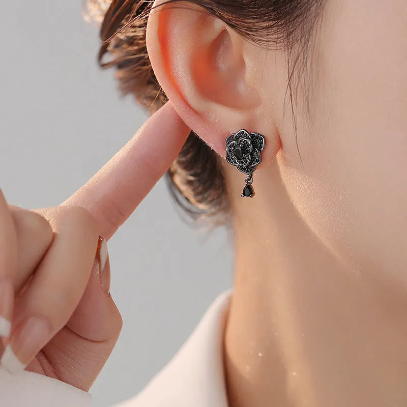 Black rose zircon inlaid stud earrings with 18K gold plated copper flower shape on white background