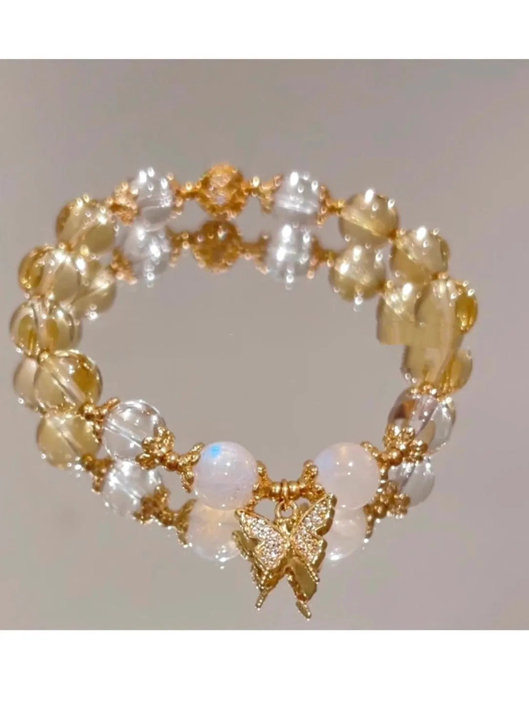 Moonstone white crystal beaded bracelet with citrine butterfly charm on display