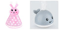 White and blue electric whale bath toy spraying water with lights on a base.