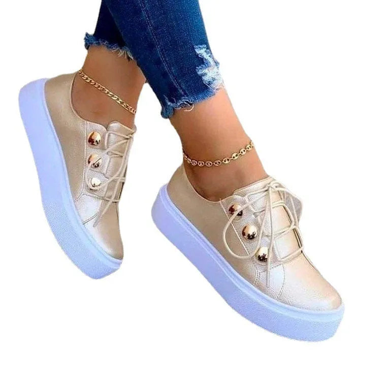 Women's white lace-up flats sneakers with silver rivet detail on a round toe.