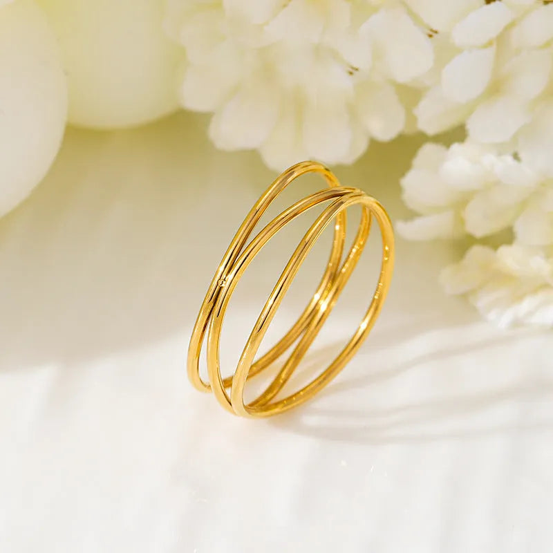 Gold geometric titanium steel ring with a three-layer coil design on a hand.