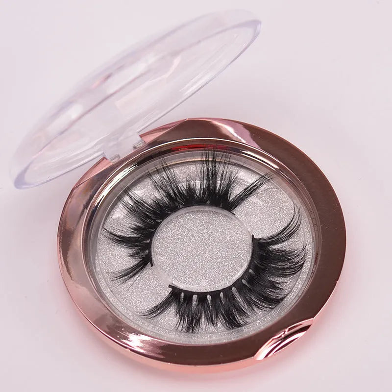 A pair of 5D mink false eyelashes with a double-headed brush and a black hair storage cap on a white background.