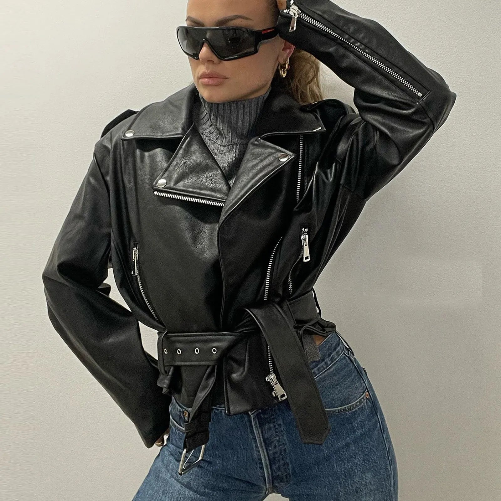 Black punk style leather jacket with a Peter Pan collar and drawstring waist on a hanger.