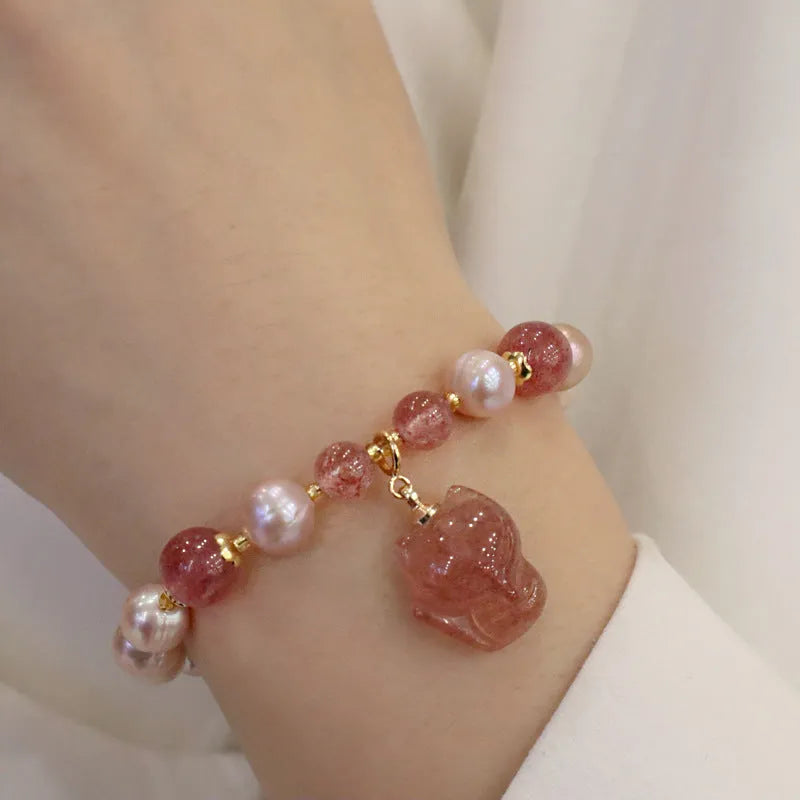 Women's natural freshwater pearl bracelet with light pink pearl, strawberry quartz, and fox charm on white background