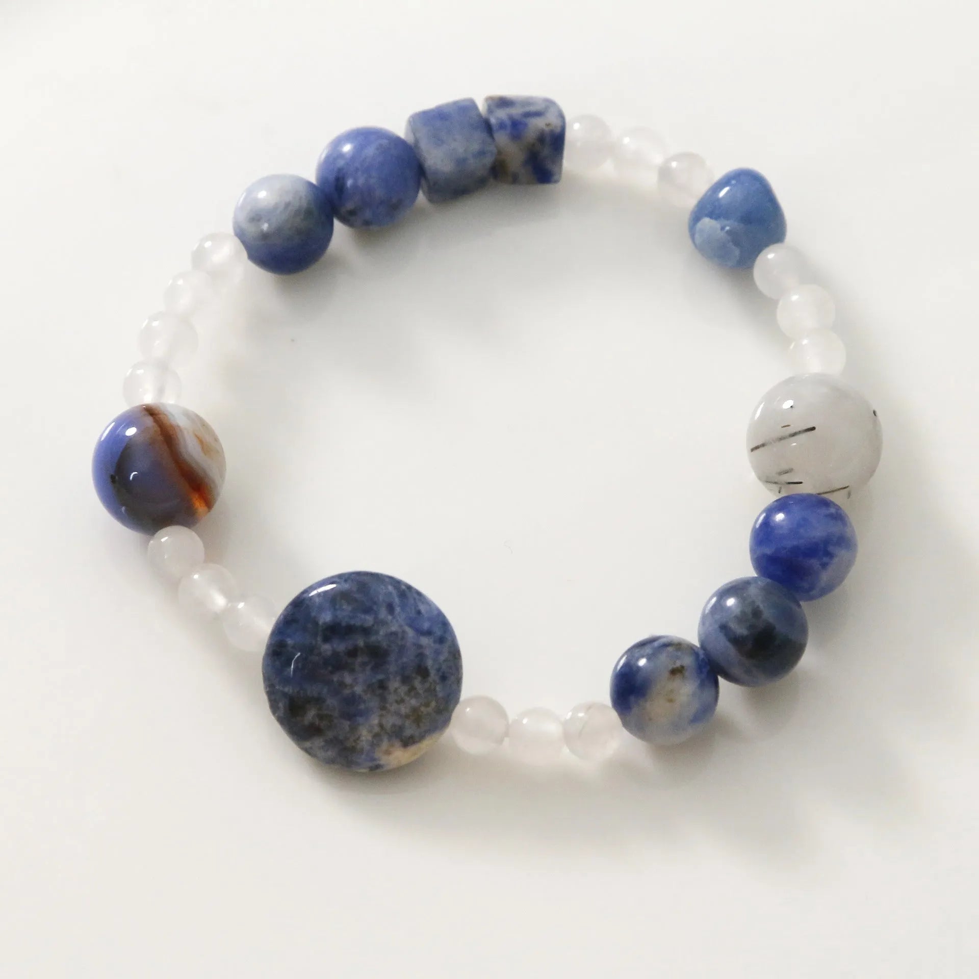 Natural blue point stone and black hair crystal agate hand-woven unisex bracelet with round and oval beads on white background