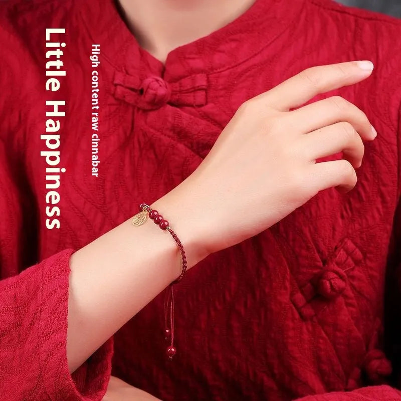 Cinnabar birth year braided rope bracelet with round bead blessing card in wine red colour on a plain background.