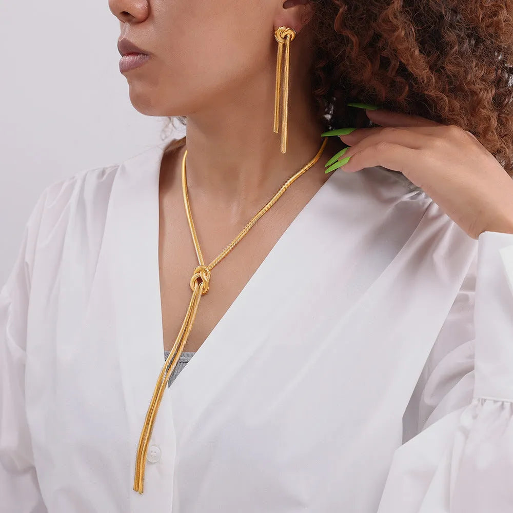 Gold knotted tassel snake chain long necklace with matching earrings on white background