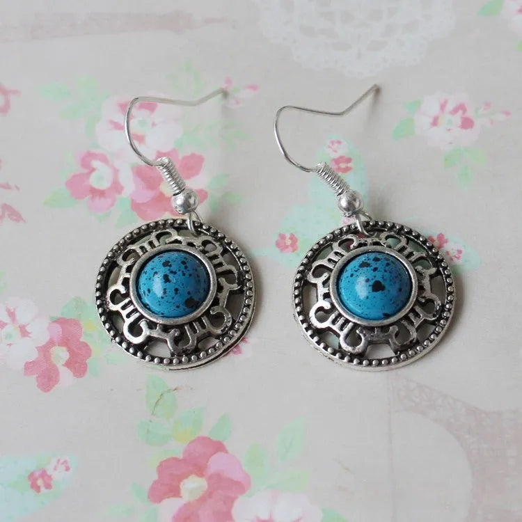 Handmade ethnic earrings with a Tibetan silver geometric flower disk design and turquoise stones.