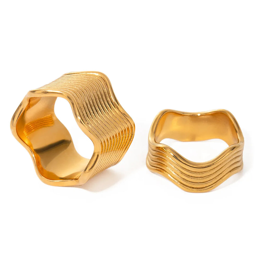 Stainless steel ring with a wide geometric wave design in a gold or silver finish.