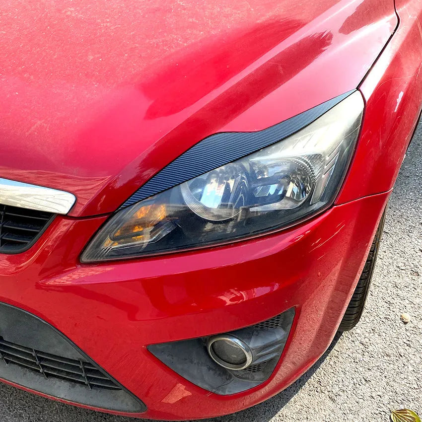 Ford Focus headlight sticker in carbon fiber pattern applied as external eyebrow trim on a car headlight