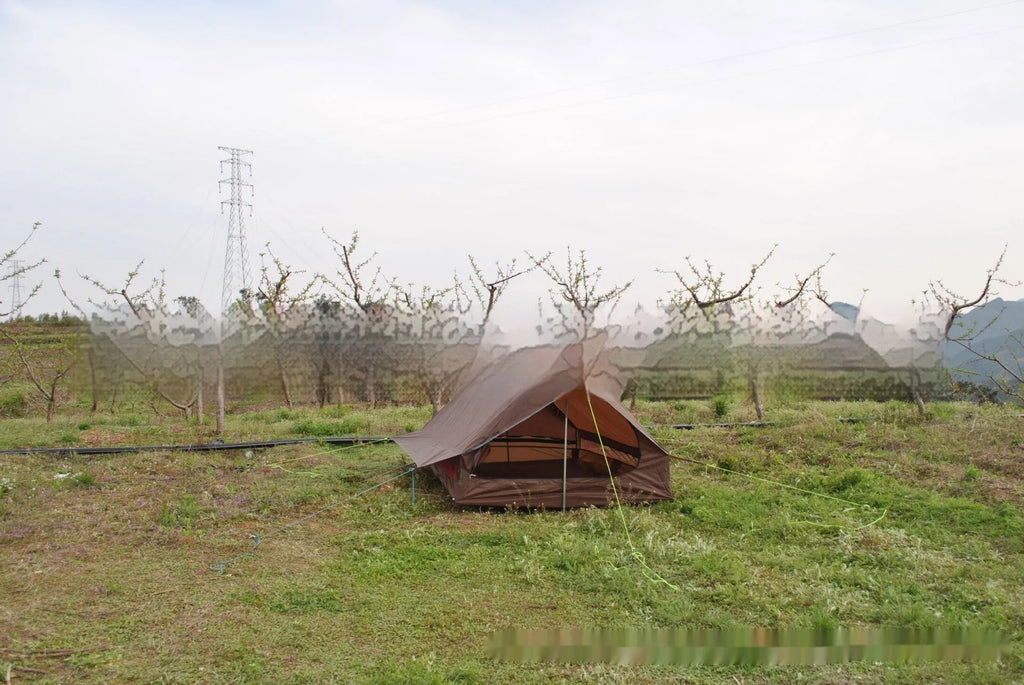 Brown A-line hiking tent set up with trekking poles in a forest clearing.
