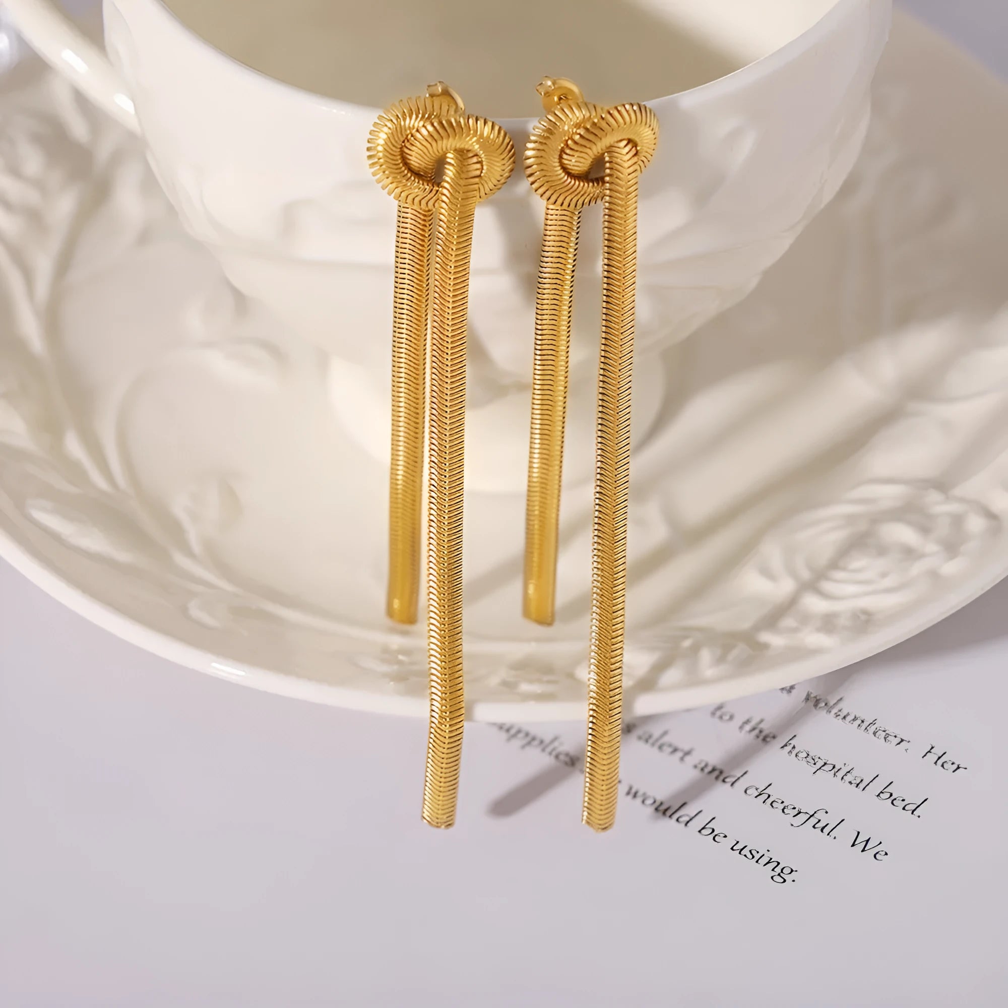 Gold knotted tassel snake chain long necklace with matching earrings on white background