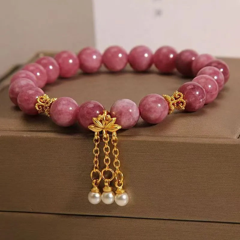 Natural stone beaded bracelet with pink lotus tassel and pearl pendant on white background