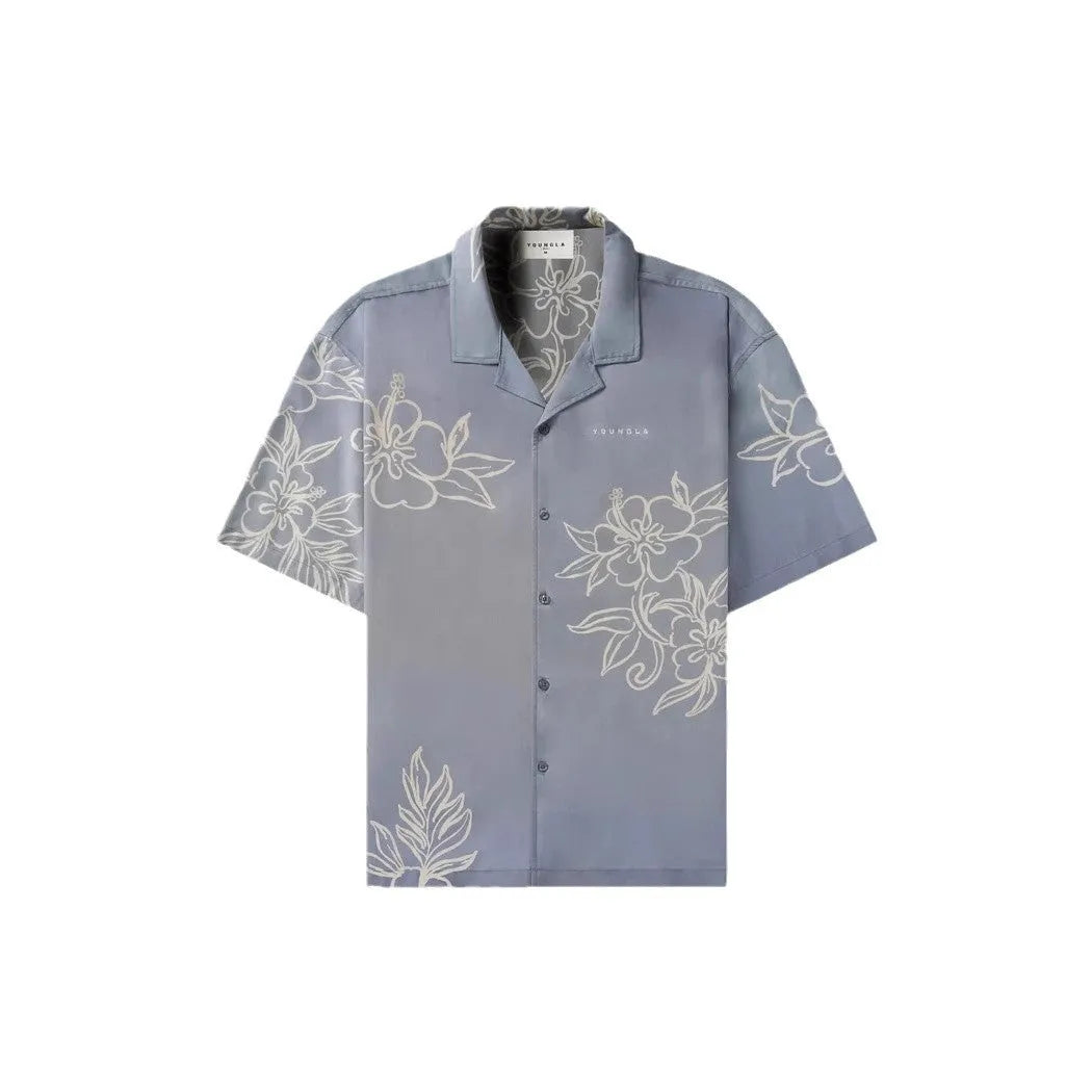 Man wearing a loose grey short-sleeve top with a floral print pattern