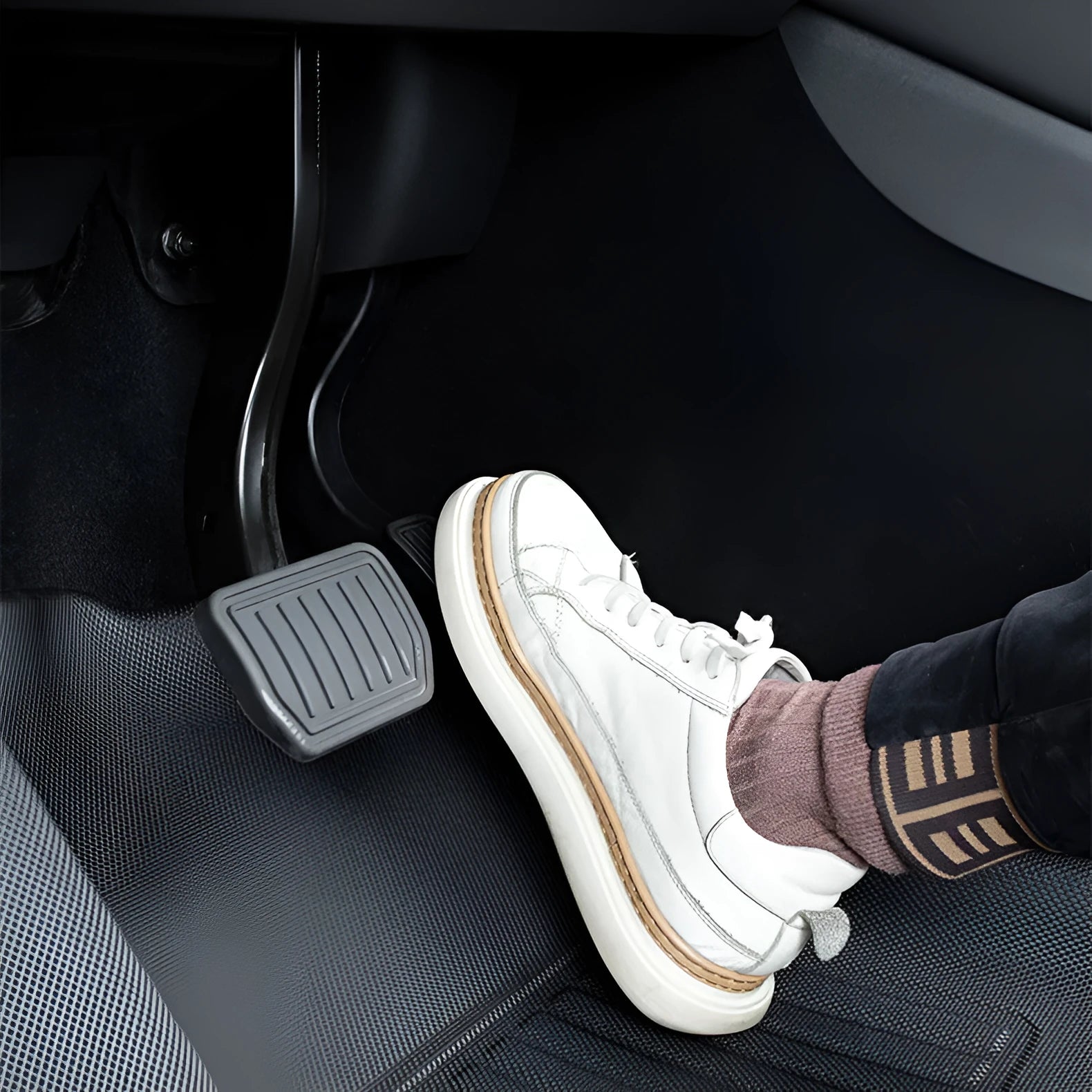 Minimalist black TPR car floor mats designed for Tesla Model Y, showing tailored fit in footwell area.