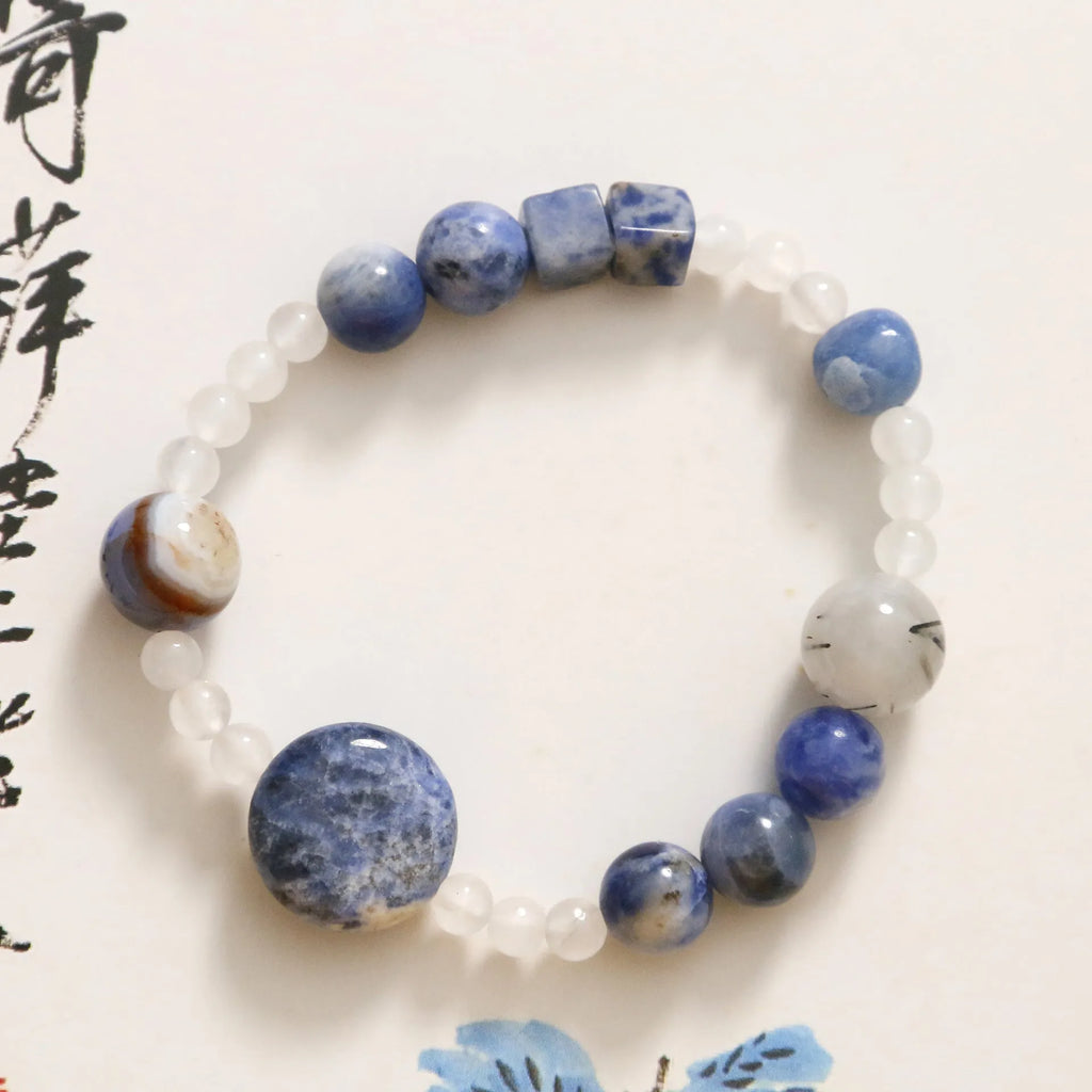 Natural blue point stone and black hair crystal agate hand-woven unisex bracelet with round and oval beads on white background