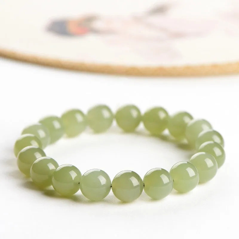 Polished Hetian jade bead bracelet in ice-clear colours on a wrist, showing spherical beads.
