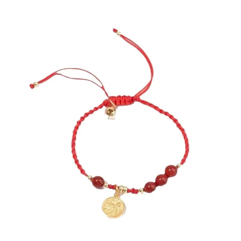 Cinnabar birth year braided rope bracelet with round bead blessing card in wine red colour on a plain background.