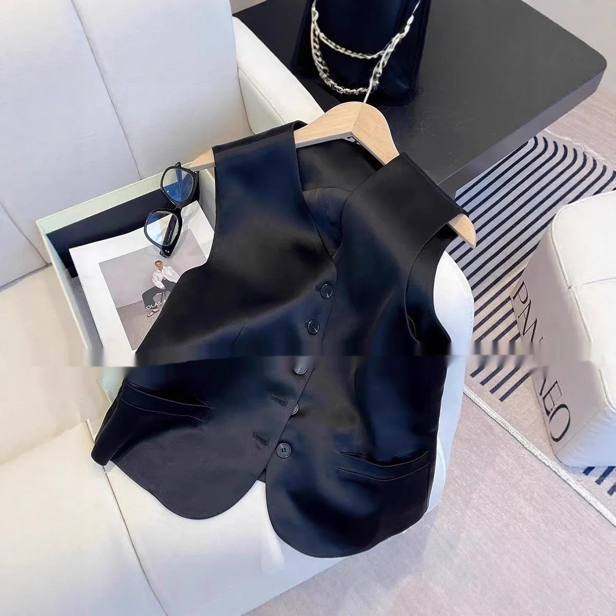 Black satin sleeveless vest for women on a hanger, showing loose fit and V-neck.