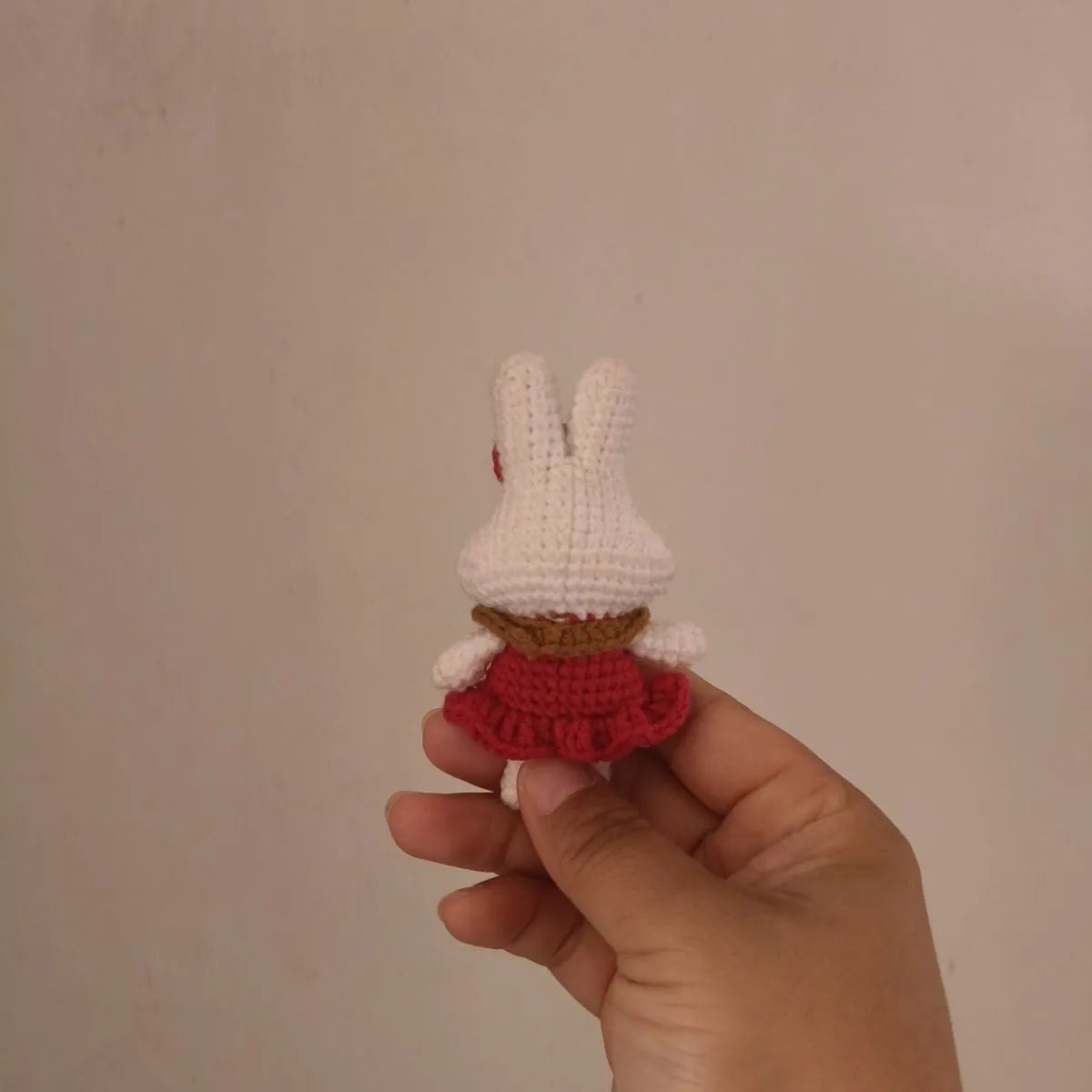 Hand-crocheted wool rabbit key chain pendant with key chain attachment on a soft surface