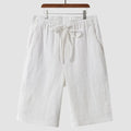 Man wearing beige linen shorts with a loose cropped fit and elasticated mid waist.