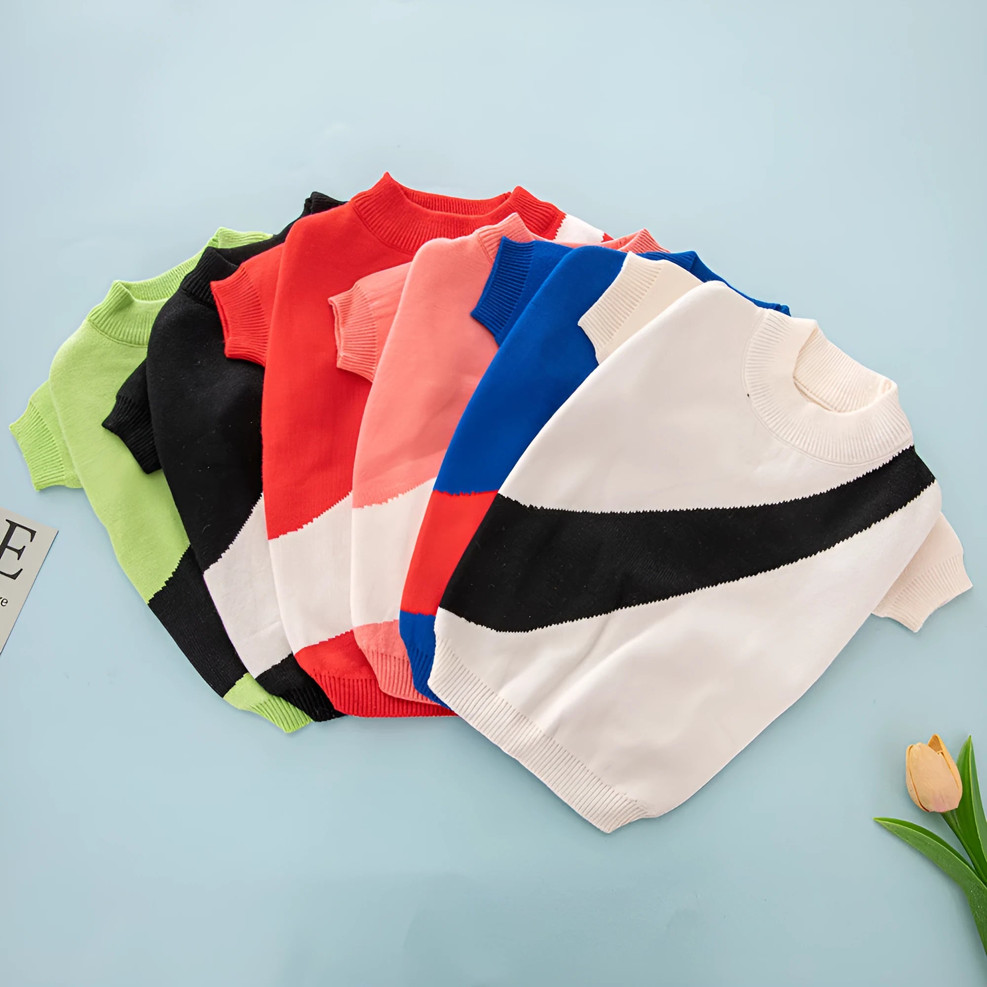 Wool knit sweater for a corgi or poodle dog on a hanger, showing colour options: black, orange red, pink, milky white, light green, sapphire blue.