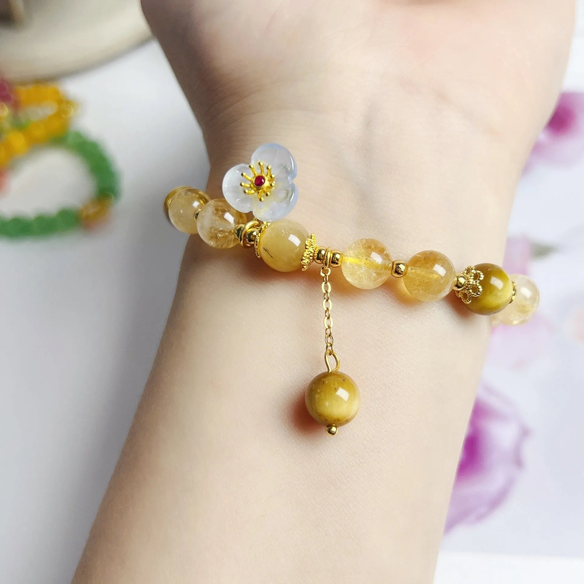 Women's handcrafted citrine crystal bracelet with flower tassel pendant on white background