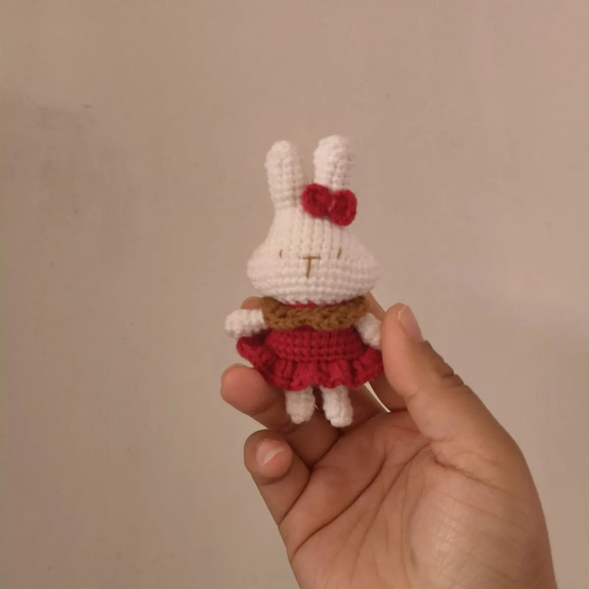 Hand-crocheted wool rabbit key chain pendant with key chain attachment on a soft surface