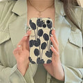 Black silicone iPhone case with a white tulip floral graphic on the back