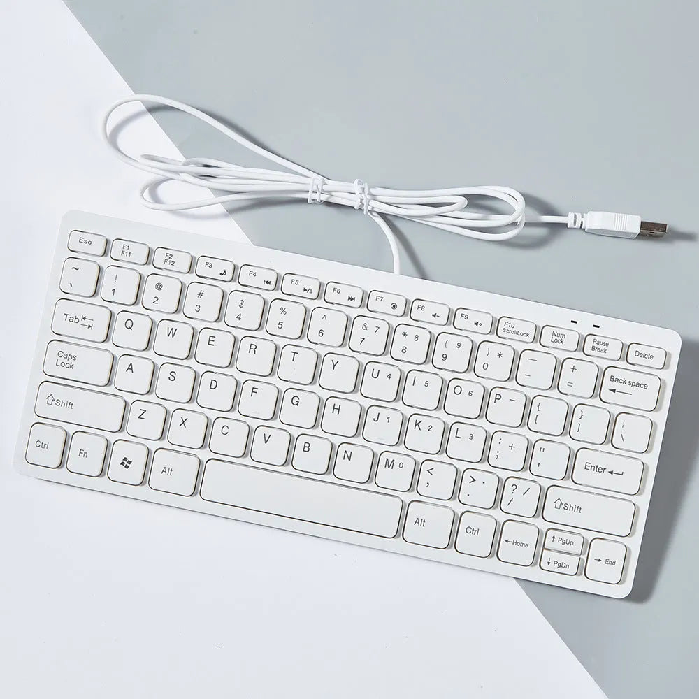 Compact wired USB mini keyboard in black, white, pink, or blue colours on a desk.