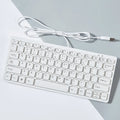 Compact wired USB mini keyboard in black, white, pink, or blue colours on a desk.