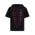 Black loose-fit men's hooded T-shirt covered in reflective sequins, shown in a casual setting.