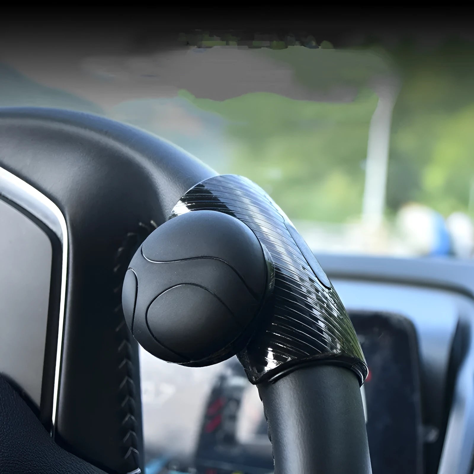 Black silicone steering wheel assist ball with metal bearing on a car steering wheel.