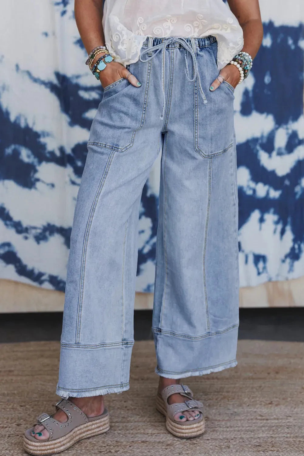 Beau Blue wide leg denim trousers on a hanger, showing drawstring waist, seam detailing, and raw hem.