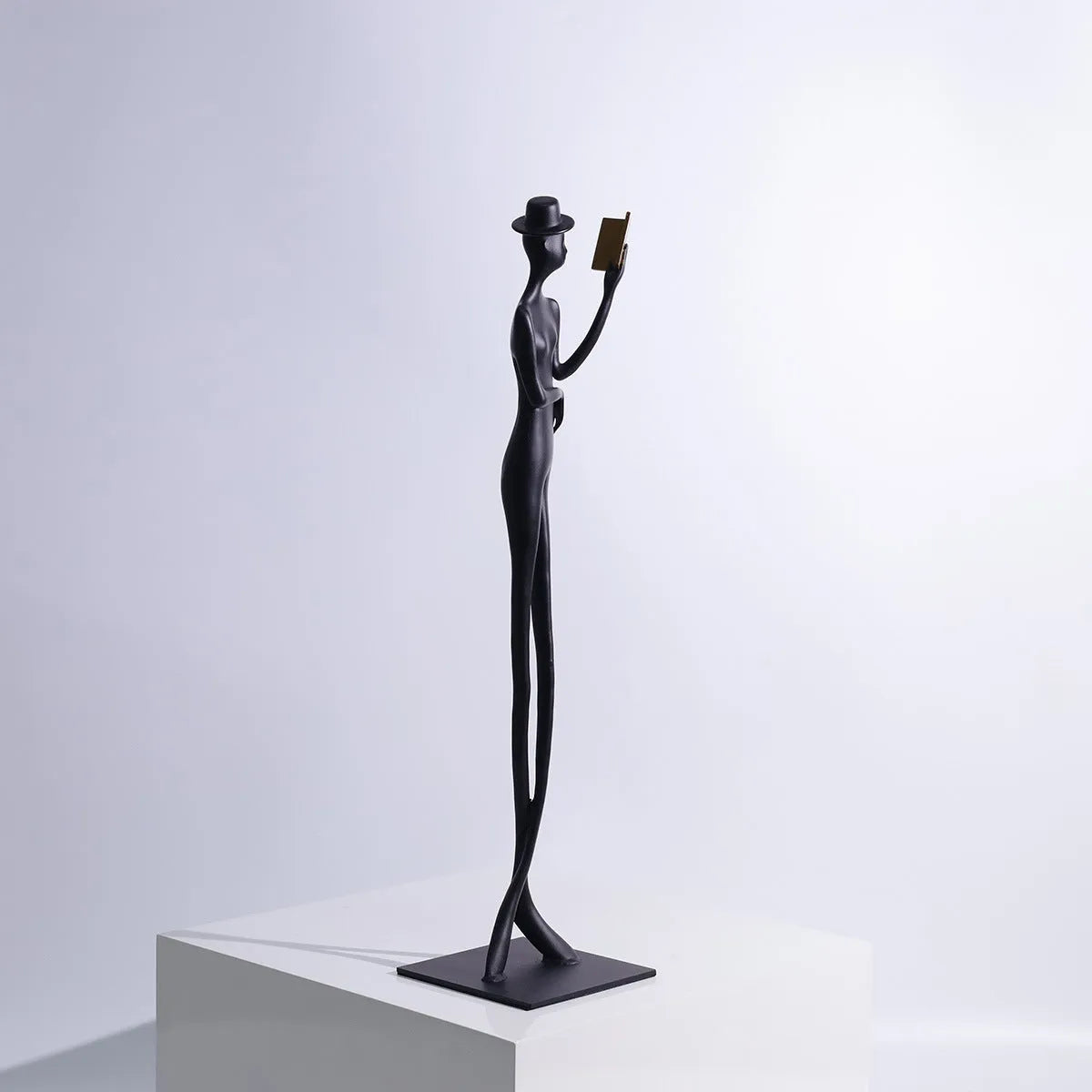 Black cast aluminium reading woman sculpture on desk, modern minimalist design