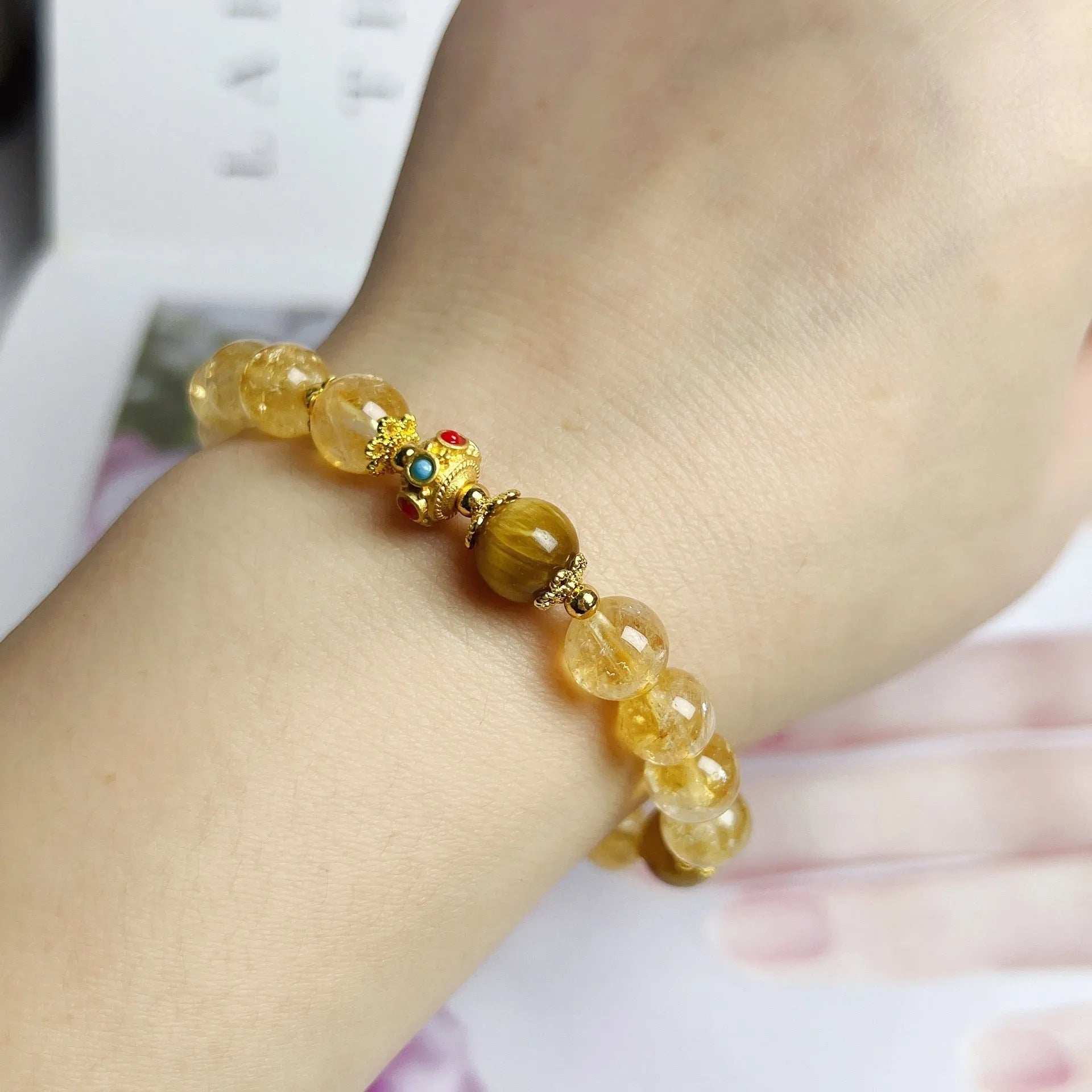 Women's handcrafted citrine crystal bracelet with flower tassel pendant on white background