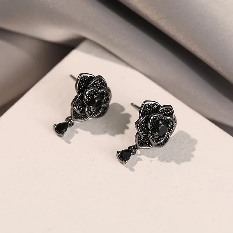 Black rose zircon inlaid stud earrings with 18K gold plated copper flower shape on white background