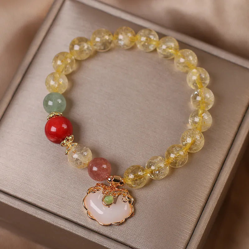 Close-up of a women's adjustable bracelet with a yellow citrine jade ruyi pendant on an alloy chain.