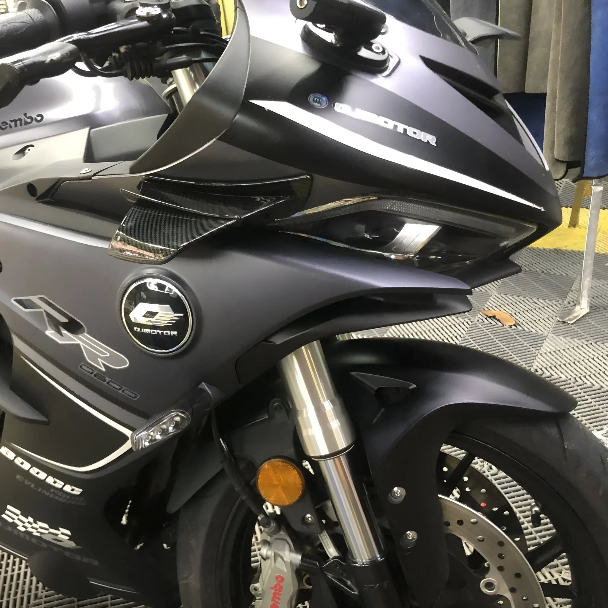 Universal motorcycle spoiler wind wings in pure black finish with glossy forged pattern, side view on a dark background.