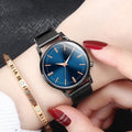 Men's and women's couple watch set with blue metal mesh band, luminous dial, and alloy case on a white background