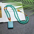 Turquoise lucky pendant necklace with hand-woven mesh flower design on an adjustable ball bead chain.