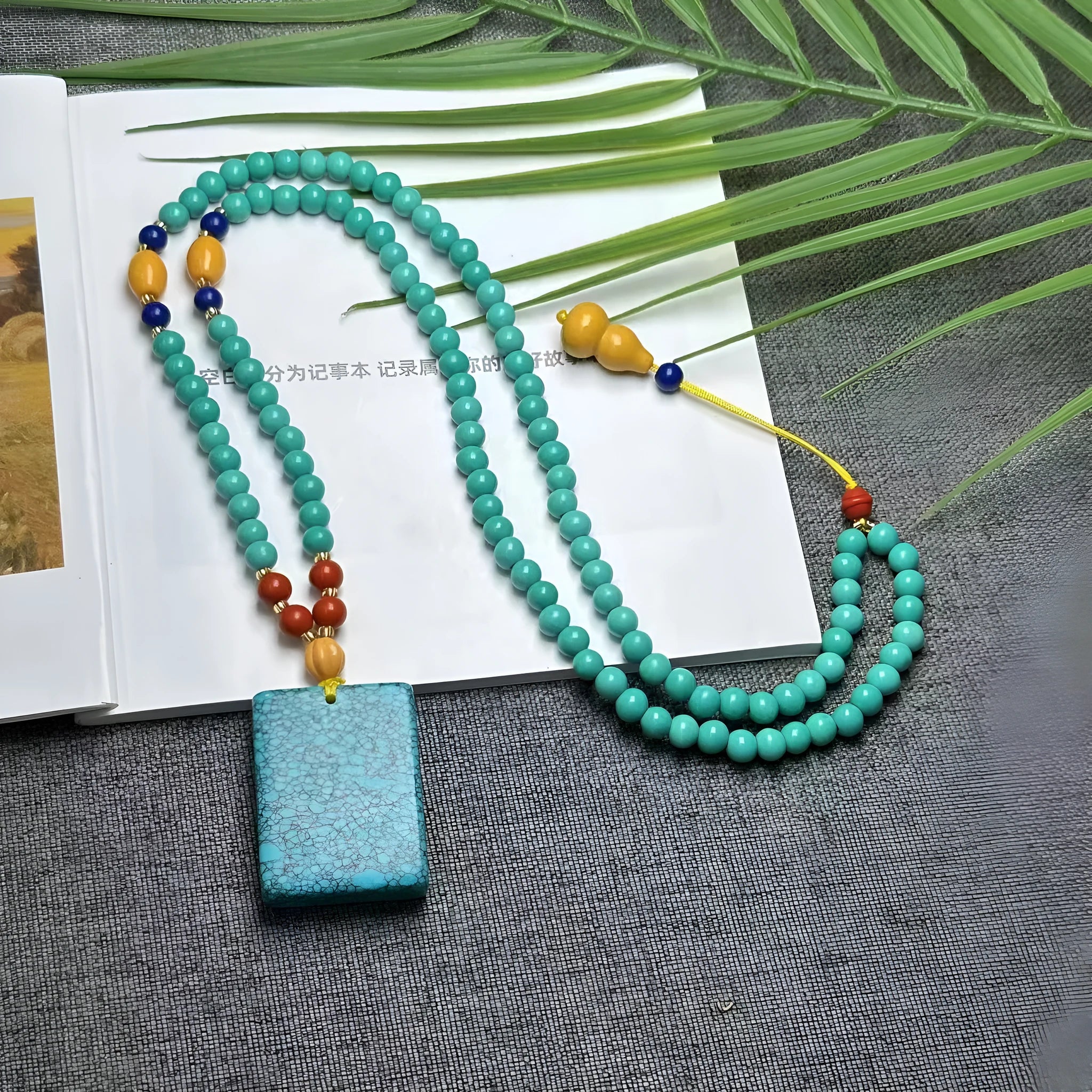 Turquoise lucky pendant necklace with hand-woven mesh flower design on an adjustable ball bead chain.