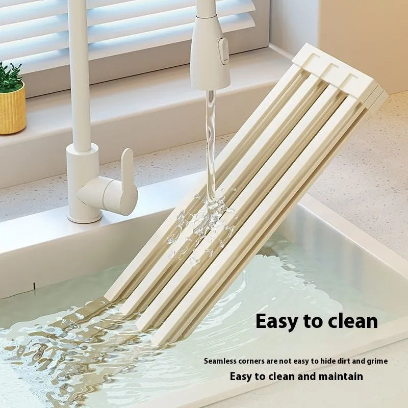 Milky white foldable stainless steel kitchen draining rack placed next to a sink.