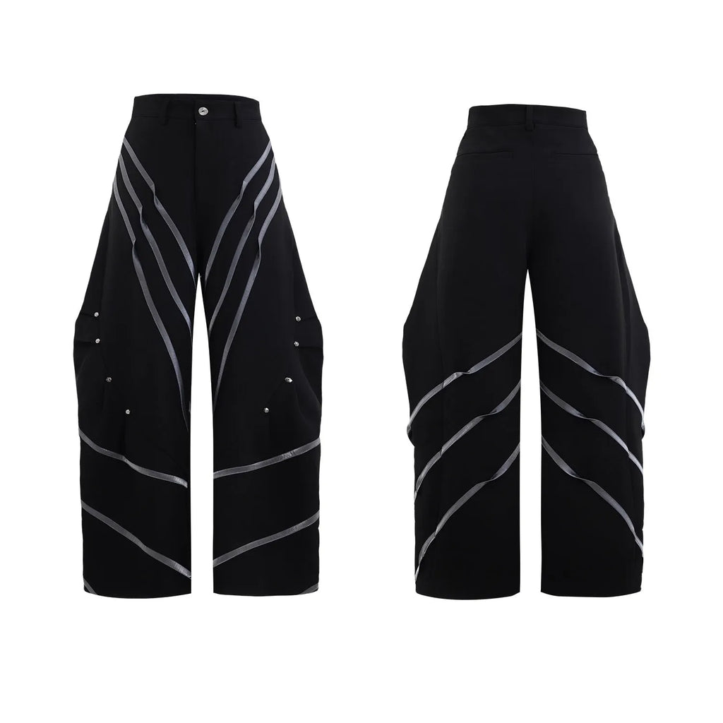 Men's black trousers with metal striped rivet details, pleated front, and a structured three-dimensional cut.