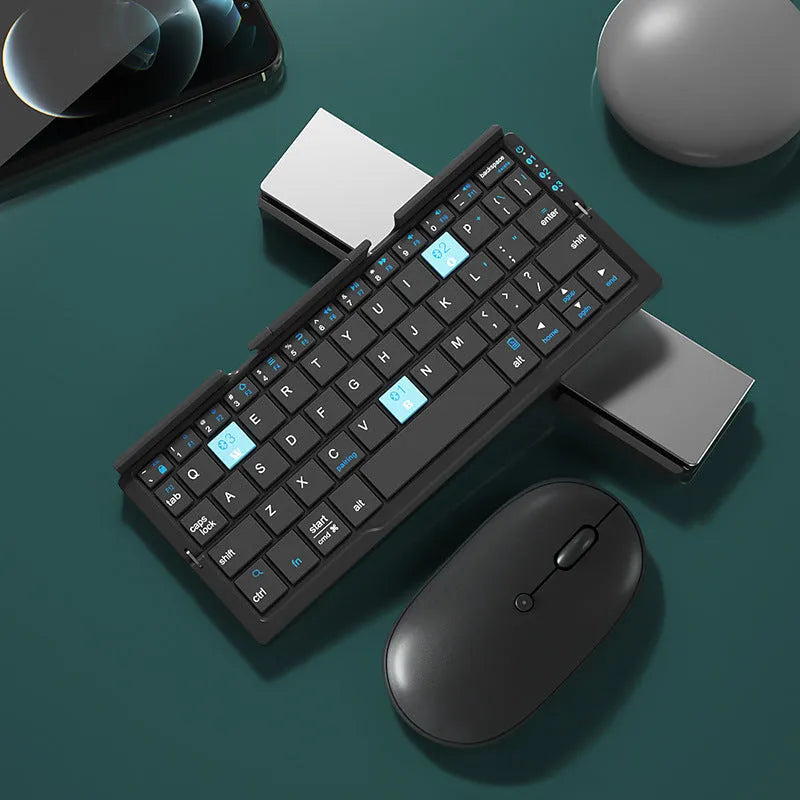 Silver white mini folding Bluetooth keyboard open next to a smartphone on its integrated stand.