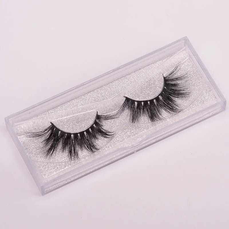A pair of 5D mink false eyelashes with a double-headed brush and a black hair storage cap on a white background.