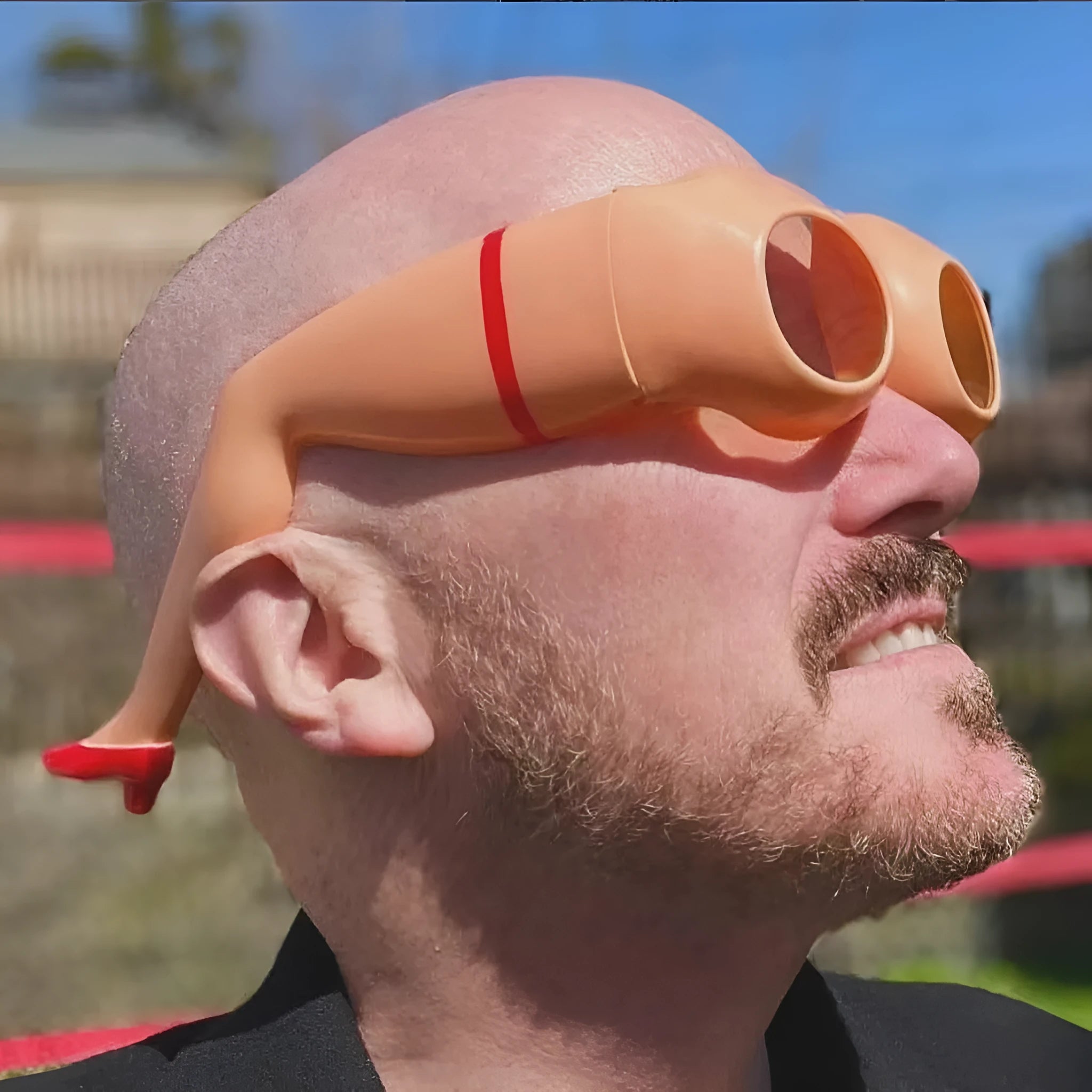 Orange plastic novelty sunglasses shaped like legs and hips on a white background.