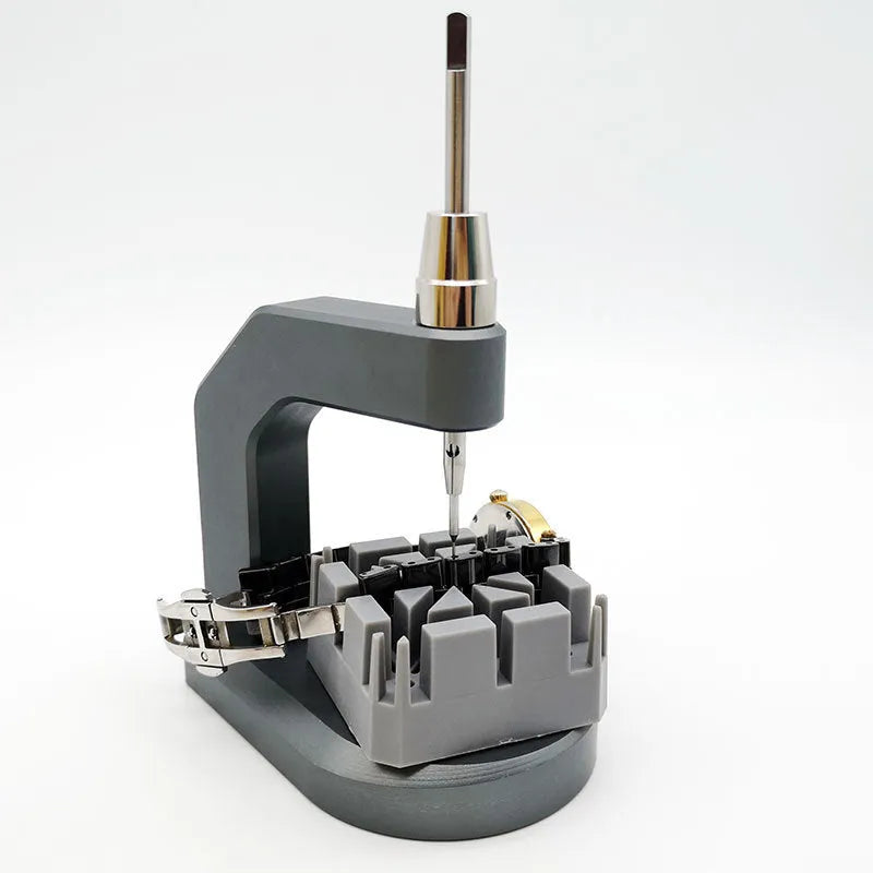Silver multi-purpose press strap removal tool made from tool steel on a work surface.