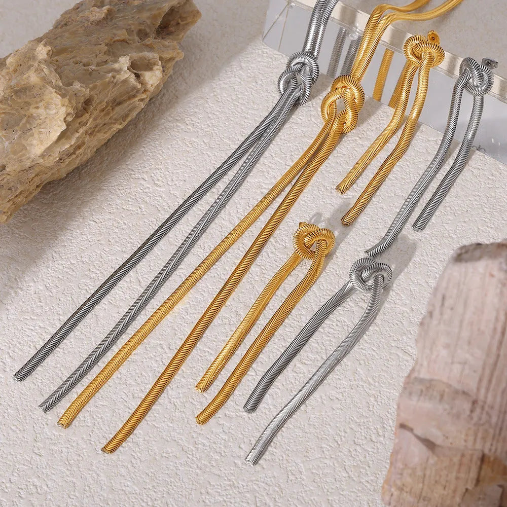 Gold knotted tassel snake chain long necklace with matching earrings on white background