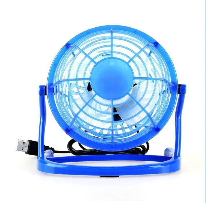Small black USB desk fan with adjustable head on a wooden desk next to a laptop